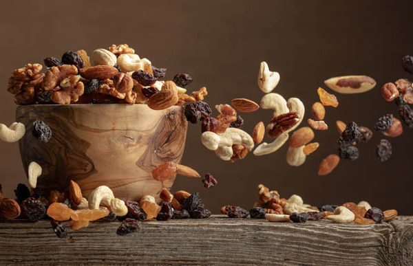 Flying dried fruits and nuts. The mix of nuts and raisins in a wooden bowl.