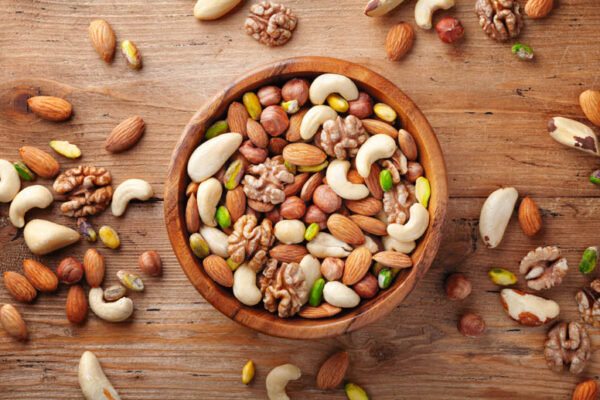 Wooden bowl with mixed nuts on rustic table top view. Healthy food and snack.