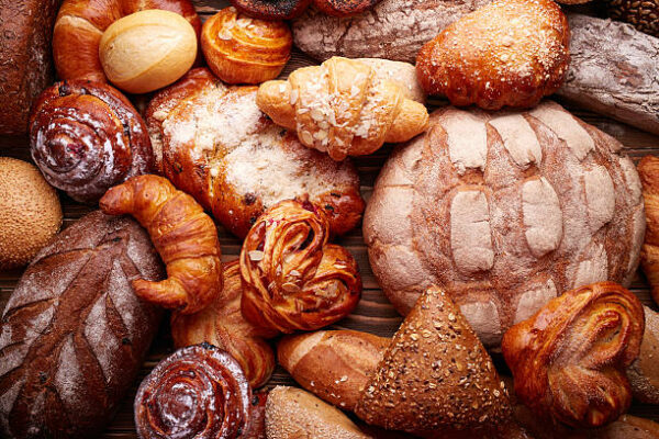 Fresh tasty bread and buns over wooden background